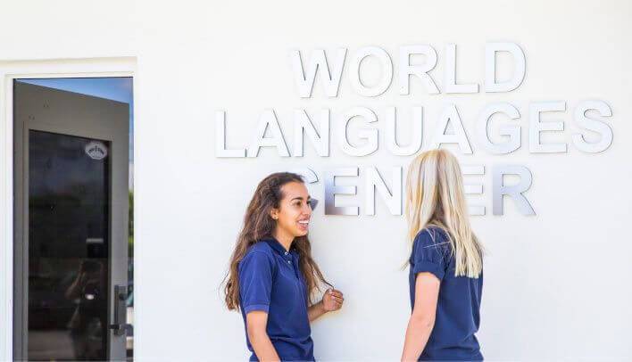 Two students standing beside the World Languages Center sign