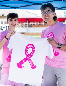 MCDS student holding a pink awareness ribbon sign for Walk of Fame event