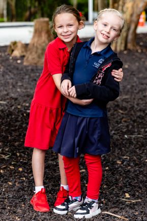 Two young students hugging and smiling together outdoors