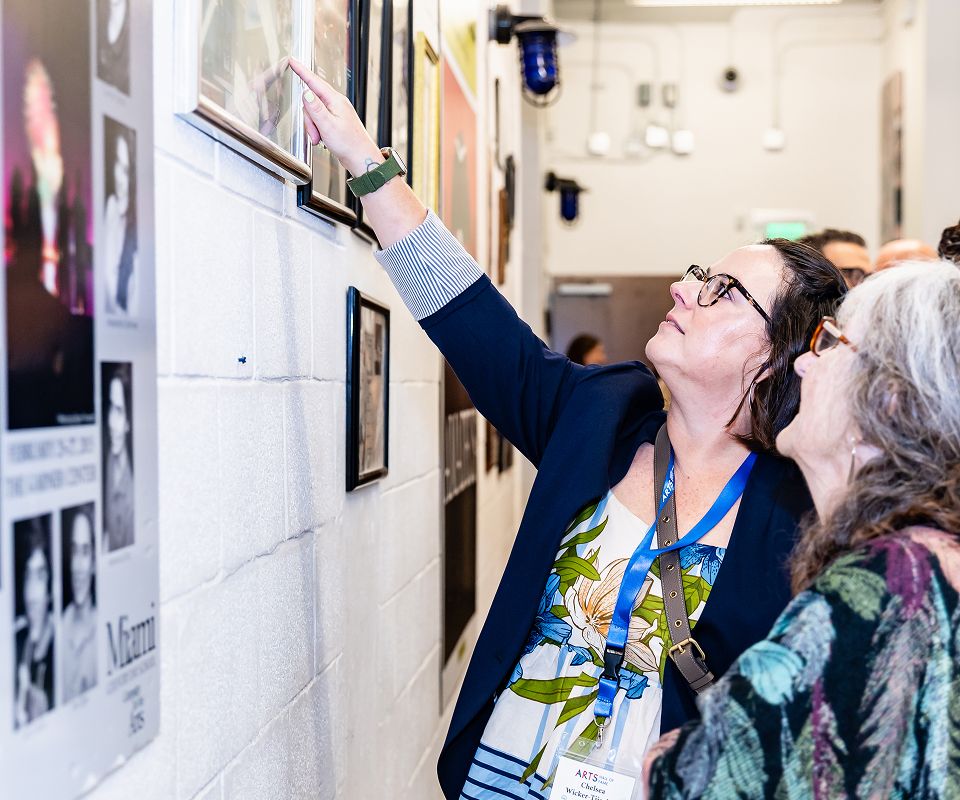 Guest pointing to a framed photograph on the Hall of Fame wall