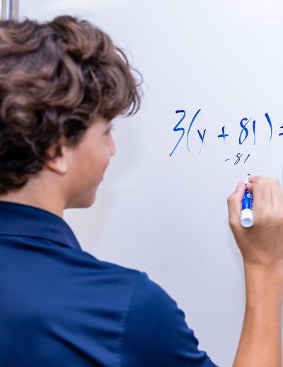 MCDS Middle School student solving a math problem on the whiteboard