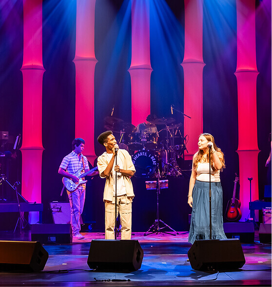 Upper School students singing and playing guitar on stage