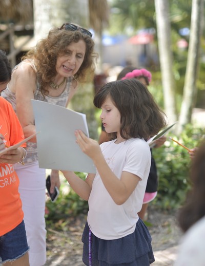 MCDS summer camp counselor guiding a student through a reading activity outdoors