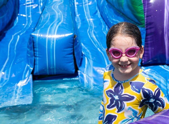 MCDS summer camper smiling on an inflatable water slide during camp