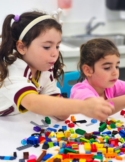 Two young MCDS day camp students building with colorful LEGO bricks