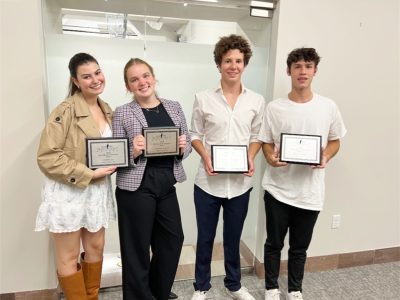 Four Upper School students holding award plaques
