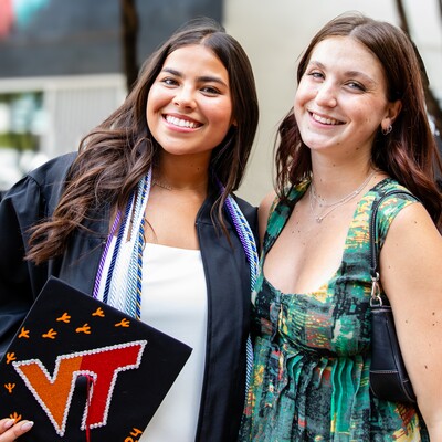 Two graduates posing together after the Commencement ceremony