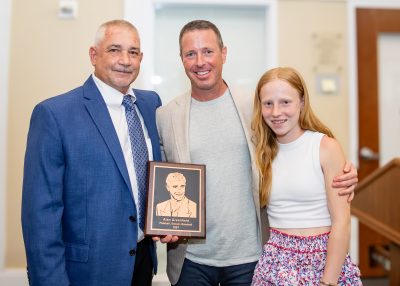MCDS Hall of Fame honoree posing with guests and a plaque