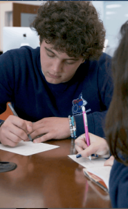 MCDS student writing at a desk, Capstone program thumbnail