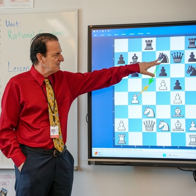 Teacher pointing at a chess board projected on a classroom screen