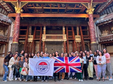MCDS students posing with a flag banner outside an ornate building, GATEway trip photo