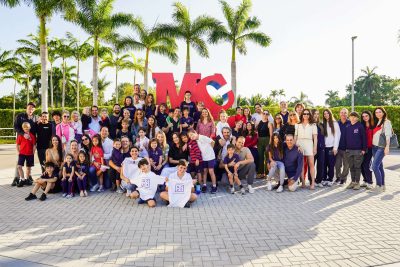 Large group of students gathered outdoors by the MCDS sign