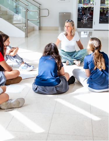 MCDS students and a staff member talking together in a circle, shown on the Our Strategic Plan page