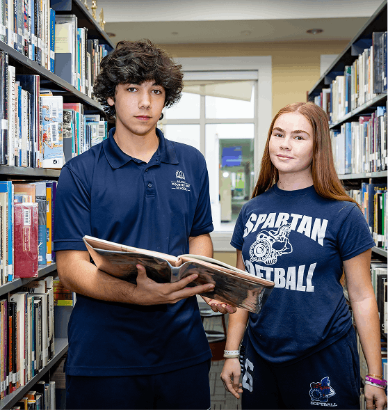 Two Upper School students looking at a book in the library