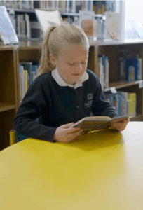 MCDS student writing at a desk, literacy program thumbnail